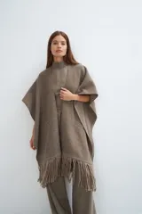 Ruana color crema de lana fina con flecos en el ruedo y bolsillos delanteros.