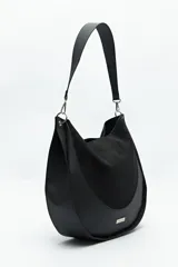 Bolso tipo hobo de cuero sintético negro con panel frontal de gamuza. Tiene correa de hombro ajustable y logo metálico plateado.