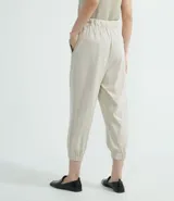 Pantalón jogger color beige, con elástico en la cintura y en los tobillos, cordón ajustable, bolsillos laterales y detalles de agujeros en los laterales y en los bolsillos.