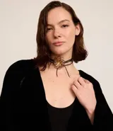 Collar choker con cordón encerado negro, puntas metalizadas y flor alambrada dorada.