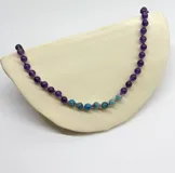 Collar de cuentas de amatista y apatita de 6mm de diámetro, separadas por nudos de hilo violeta. Cierre de mosquetón de acero hipoalergénico con baño dorado.