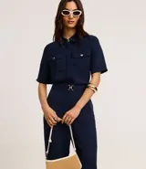 Pantalón zanahoria de cintura alta, confeccionado en tejido airflow color azul marino, con trabillas, cintura elástica y hebillas metalizadas.