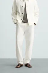 Pantalón de jean color blanco, corte recto, con bolsillos frontales y traseros, y cierre frontal con cremallera y botón.