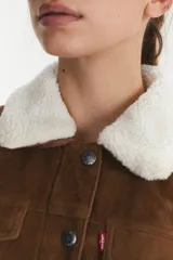 Campera Levi's color marrón con forro de sherpa blanco en el cuello. Es de gamuza sintética con cierre de botones y bolsillos en el pecho.