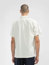 Camisa de manga corta color crema, con cuello camp y calce relajado. Confeccionada en una mezcla de lino y algodón, con botones de madera y parche característico de Polonio.