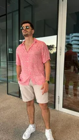 Camisa de fibrana color rosa con estampado de líneas verticales blancas, de manga corta y cuello clásico.