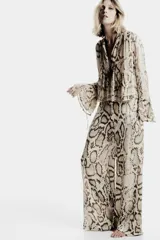 Blusa de viscosa con estampado de piel de serpiente en tonos beige y marrón. Tiene cuello redondo con lazo ajustable, mangas largas acampanadas con cordones en los puños y bajo recto.