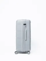 Valija rígida de viaje color gris con diseño de líneas horizontales. Cuenta con manija extensible, cuatro ruedas con giro de 360°, cierre con combinación y manija lateral.