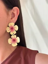 Aros colgantes con forma de flor, color amarillo y centro rosado.