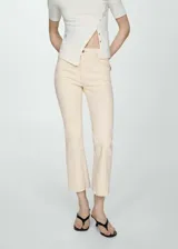 Pantalón de jean color crema, de corte flare y tiro alto, con cinco bolsillos y ruedo desflecado.