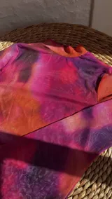Top de malla traslúcida con cuello alto y mangas largas, con estampado abstracto en tonos fucsia, naranja y violeta.