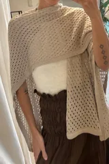 Ruana de tejido artesanal color beige, con diseño de puntos calados y mangas anchas.
