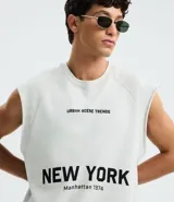 Musculosa negra de algodón con corte recto y hombros ligeramente ampliados (boxy fit). Presenta estampado frontal en blanco con el texto "URBAN SCENE TRENDS", "NEW YORK" y "Manhattan 1974".