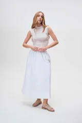 Sandalias bajas de cuero color beige con detalle de tachas metálicas en la tira delantera.