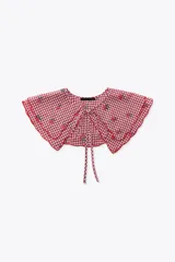 Cuello desmontable con estampado de cuadros vichy rojos y blancos, detalle de flores bordadas y volados en el borde. Se ata al frente con lazos del mismo tejido.