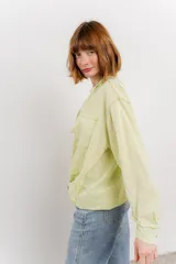 Camisa color crema de manga larga con cuello camisero y detalles de encaje en el escote. Se ata en la parte delantera.