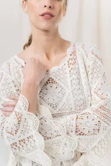 Blusa tejida calada color crudo, con diseño geométrico y motivos florales, escote redondeado y mangas 3/4 con leve vuelo.