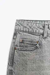 Pantalón de jean azul de tiro alto, corte mom fit, tobillero y con cinco bolsillos. Cierre frontal con cremallera y botón.