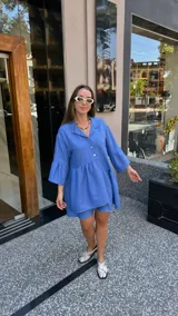 Vestido corto de manga larga con volados, color lavanda, con cuello camisero y botones frontales.