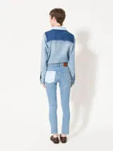 Jeans de tiro medio con calce slim y corte recto en el tobillo. Presenta roturas, lavados y parches de denim en diferentes tonos de azul.