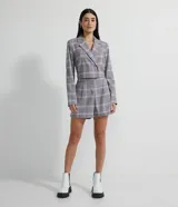 Short sastrero gris con estampado a cuadros blancos, amarillos y rosados. Tiene cintura media, pliegues, bolsillos y cierre frontal con cremallera.