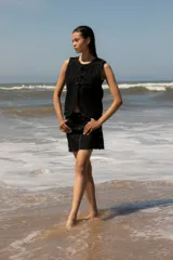 Chaleco de denim negro sin mangas con cuello redondo y costuras en contraste. Presenta un parche de cuero marrón en la parte posterior con el logo de la marca Be Ganesha. Confeccionado en tejido de algodón.