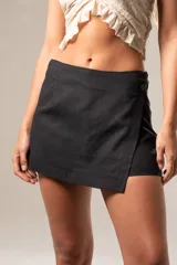 Short pollera color negro confeccionado en viscosa, poliéster y lino, con cierre de botón lateral.