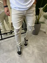 Pantalón de jean skinny color arena con roturas en las rodillas.