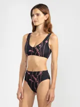 Top de bikini negro con estampado de cadenas y flores rosas.
