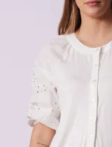 Blusa blanca de cuello redondo con apertura central y botones. Mangas 3/4 con detalle de bordado calado.