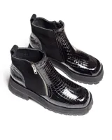 Botines negros de cuero con caña baja, puntera redondeada y cierre frontal con cremallera. Presentan paneles laterales de gamuza y suela track con plataforma.