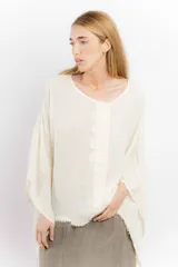Blusa color ladrillo de lino con cuello redondo y mangas largas amplias. Presenta detalle de apliques rectangulares verticales en el frente.