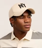 Gorra de béisbol color beige con bordado "NY" en negro.
