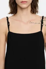 Vestido largo negro de punto con corte ajustado en la cadera y falda con vuelo, escote recto y tirantes dobles con aros metálicos y nudos.