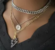 Set de tres collares de diferentes largos y estilos. El primero es una cadena gruesa plateada, el segundo es una cadena fina plateada con un dije de moneda y el tercero es una cadena dorada con un dije de rayo.