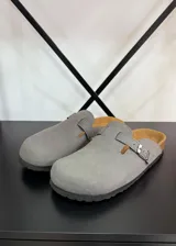 Zuecos grises con plantilla color cuero y hebilla plateada ajustable.