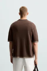 Camisa marrón de punto con viscosa, corte relaxed fit, cuello solapa, manga corta, rib a contraste y cierre frontal con botones.