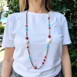 Collar largo con cadena plateada de eslabones y piedras de coral, turquesa y nácar. Incluye dijes en forma de corazón de nácar.