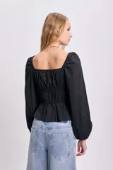 Blusa negra de punto smock con escote cuadrado, mangas largas abullonadas y corte peplum.