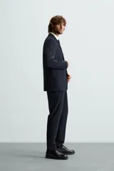 Pantalón de vestir color verde oliva, corte slim fit, con bolsillos laterales y traseros de ojal con botón. Cierre frontal con cremallera y botón.