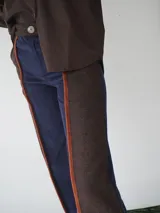 Pantalón de paño combinado con tira de cuero color naranja en los laterales.