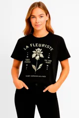 Remera negra de algodón con estampado frontal de una flor y texto en francés. El texto dice 'La Fleuriste', '1984 Paris', 'Rue Saint-Benoit' y 'Saint-Germain-des-Prés'.