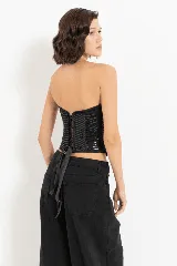 Corset negro con copas preformadas, ballenas y cierre trasero con ganchos. El cuerpo del corset está confeccionado en tejido con lentejuelas dispuestas en forma de chevron.