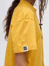 Remera amarilla de corte cuadrado y holgado, con estampado de estrella plateada con borde negro en el frente.