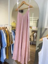 Vestido largo de lino color rosado, con escote en V y tirantes finos. Diseño de corte holgado y fluido.
