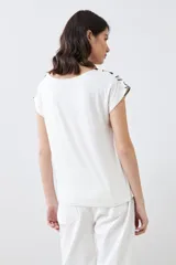 Blusa de manga corta con estampado geométrico en tonos beige, blanco y negro.