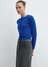 Cardigan azul de tejido de punto fino con cuello redondo, manga larga y cierre frontal con botones. Diseño recto y terminaciones en canalé.