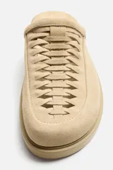 Zueco color beige de piel con acabado serraje, detalle trenzado en el empeine, plantilla acolchada y suela con volumen.