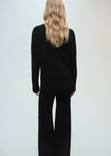 Jersey negro de punto fino con cuello alto, diseño oversize y manga larga.