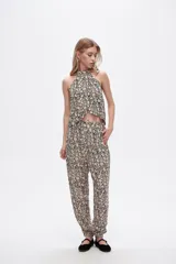 Pantalón slouchy de viscosa con estampado floral en tonos beige y negro, bolsillos laterales, cintura alta y detalle de punto smock en los tobillos.